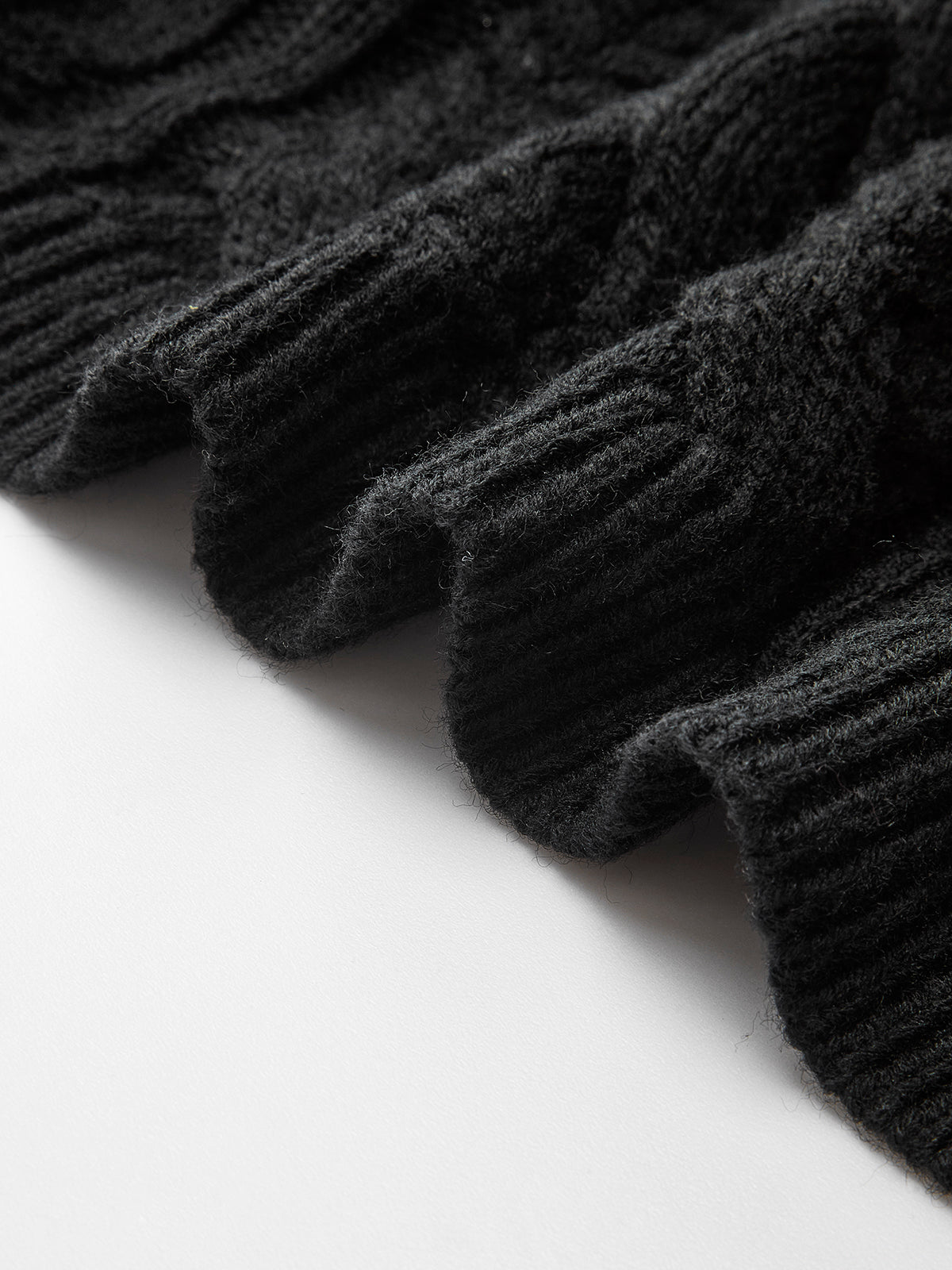 Ribbed edge of cable knit cardigan with bow-knot accent, textured knit and wavy hem.