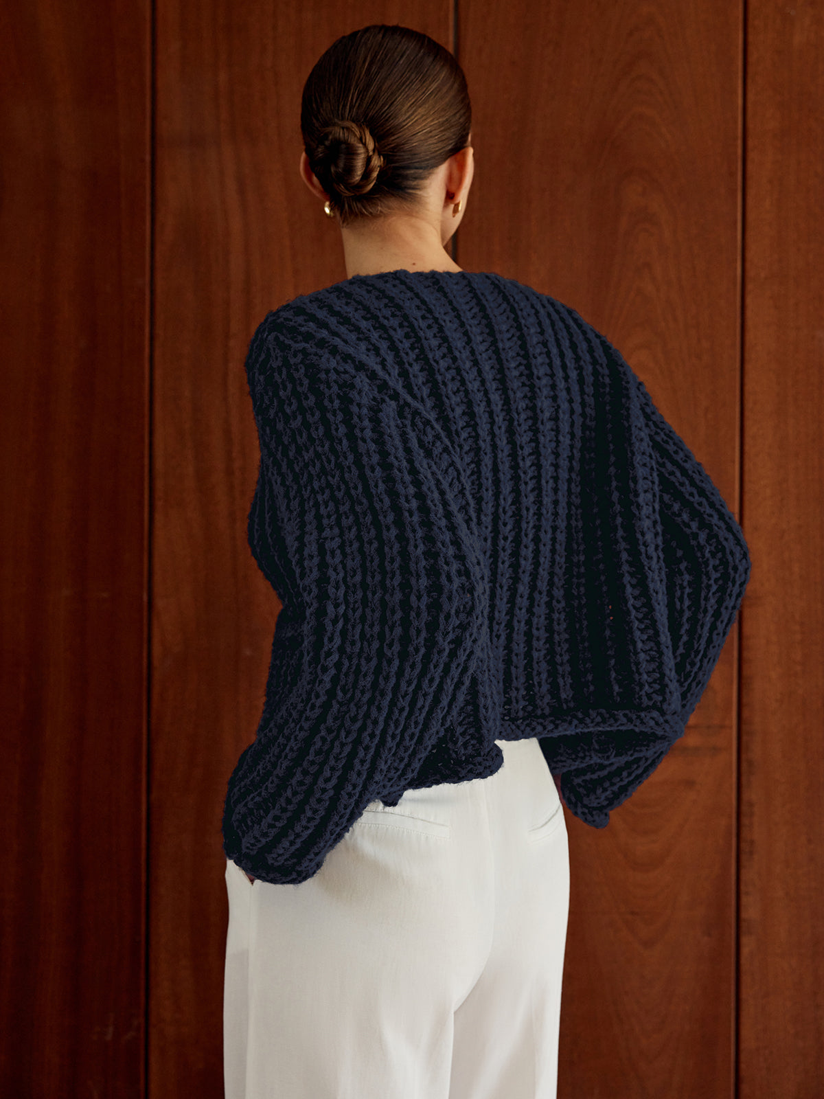 Navy blue relaxed-fit soft knit button-up cardigan paired with white pants.