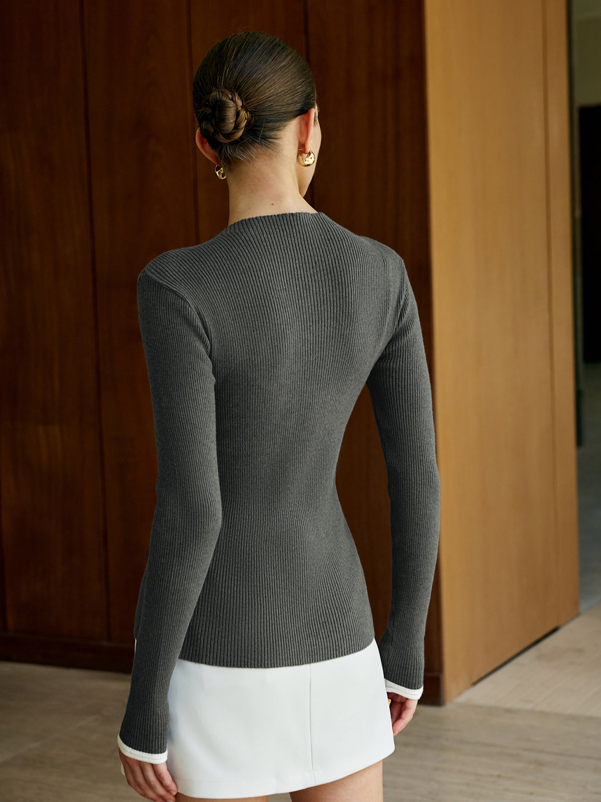 A gray classic knitted cardigan with button closure paired with a simple white skirt.