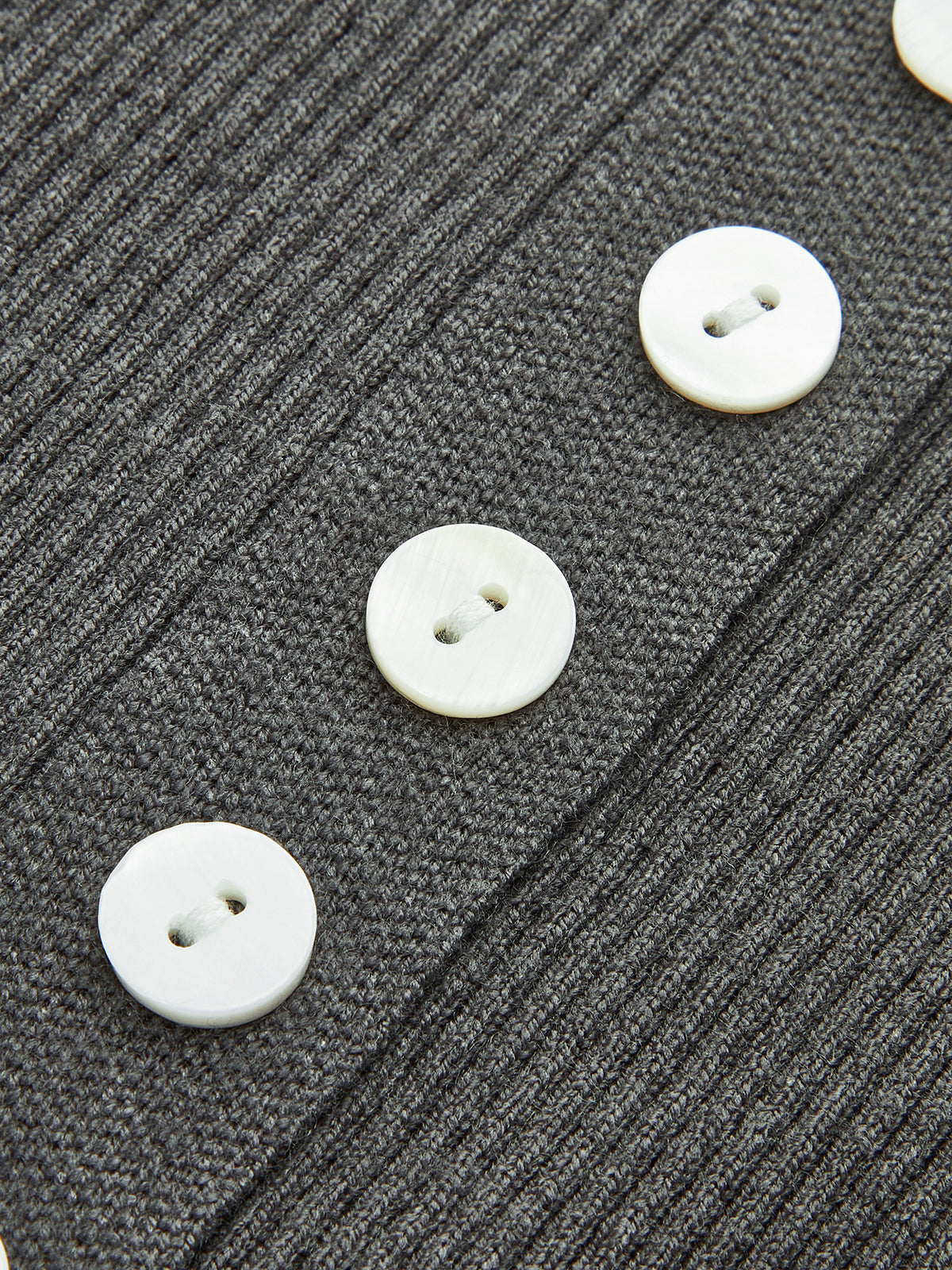 Classic knitted cardigan in textured dark gray ribbed knit with large contrasting white buttons.