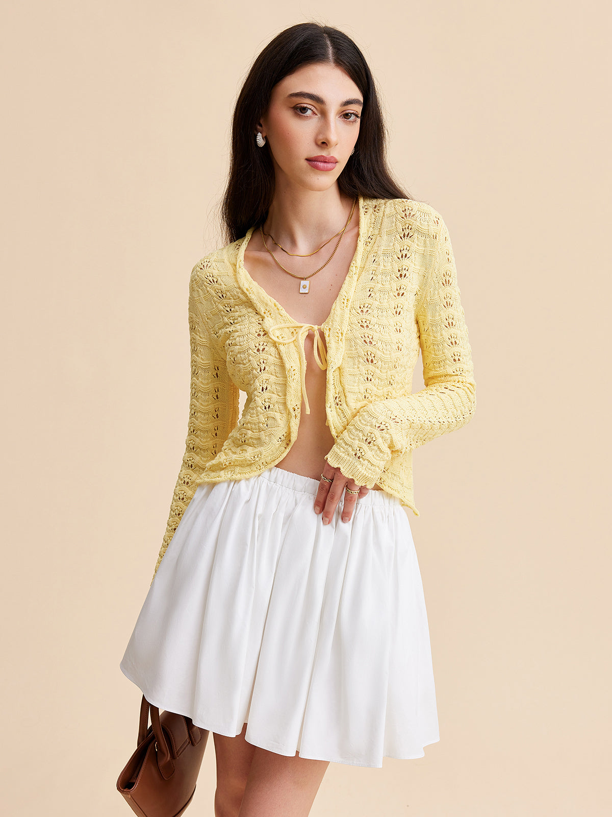 KOAD'CLO Crocheted Cardigan Sweater with tie-front, worn over a white mini skirt.