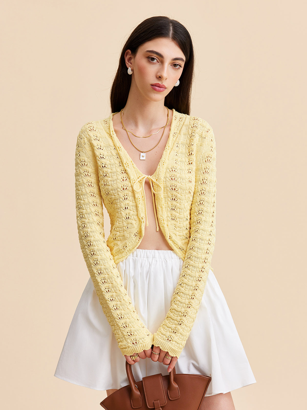 Yellow KOAD'CLO crocheted cardigan sweater with tie-front over a white top and skirt.