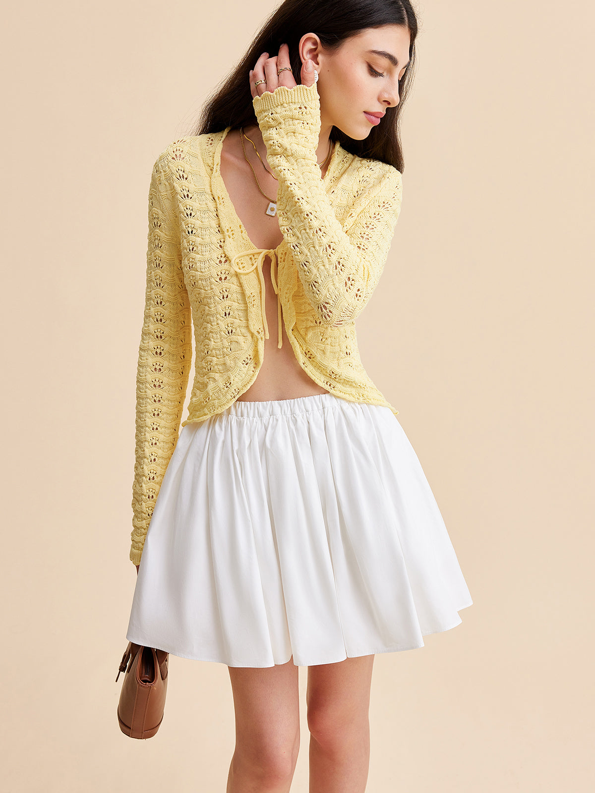 A KOAD'CLO crocheted tie-front cardigan layered over a white crop top and flared skirt.
