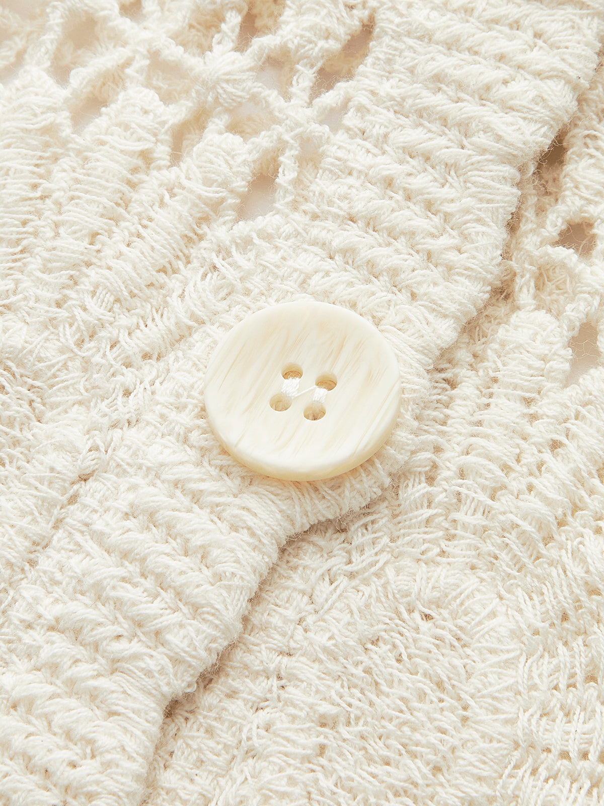 Cream floral crochet cardigan with large round button and openwork, showcasing chic texture.