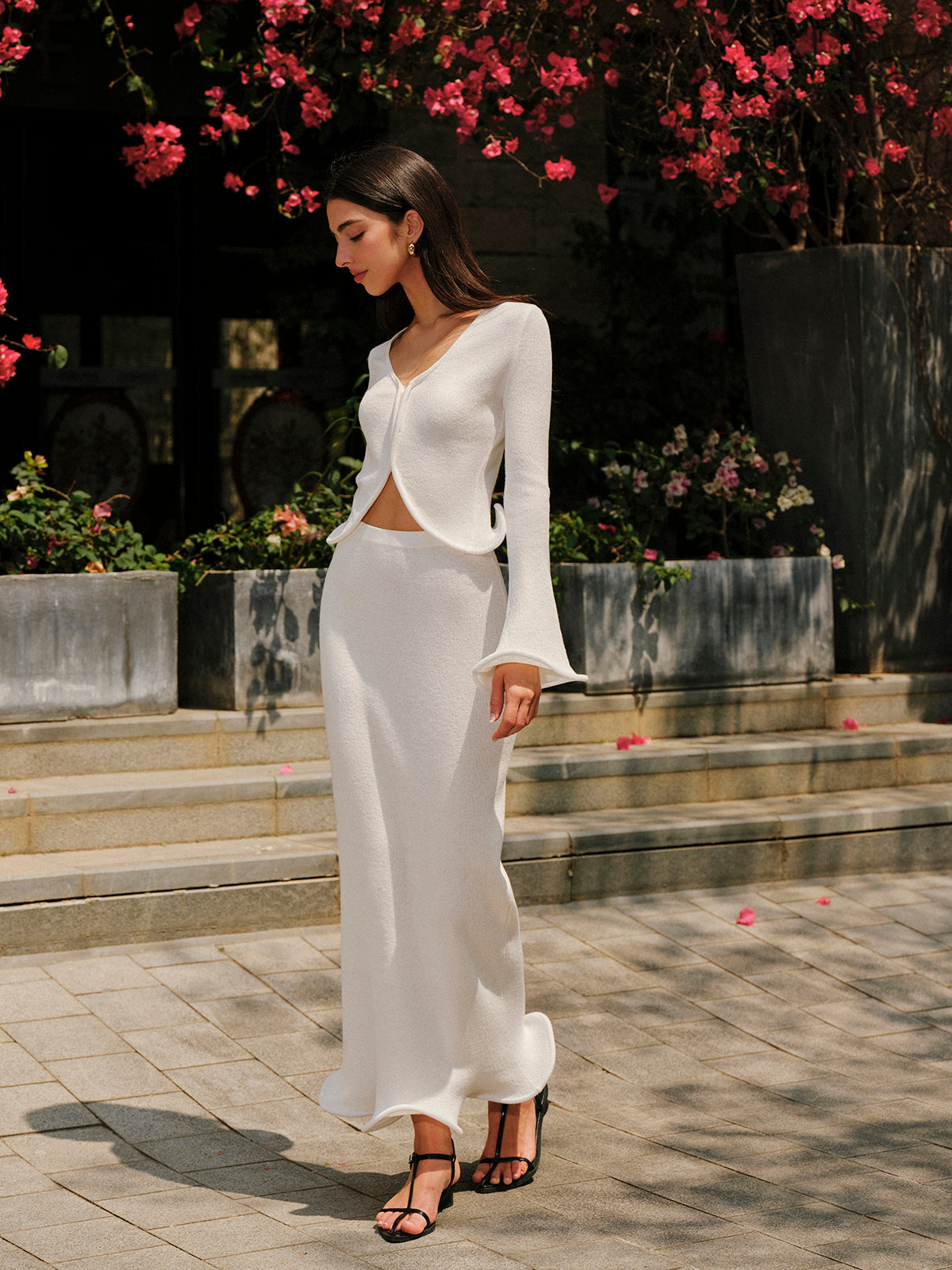 A long white skirt paired with the KOAD'CLO Ruffled Hem Knit Cardigan Sweater.