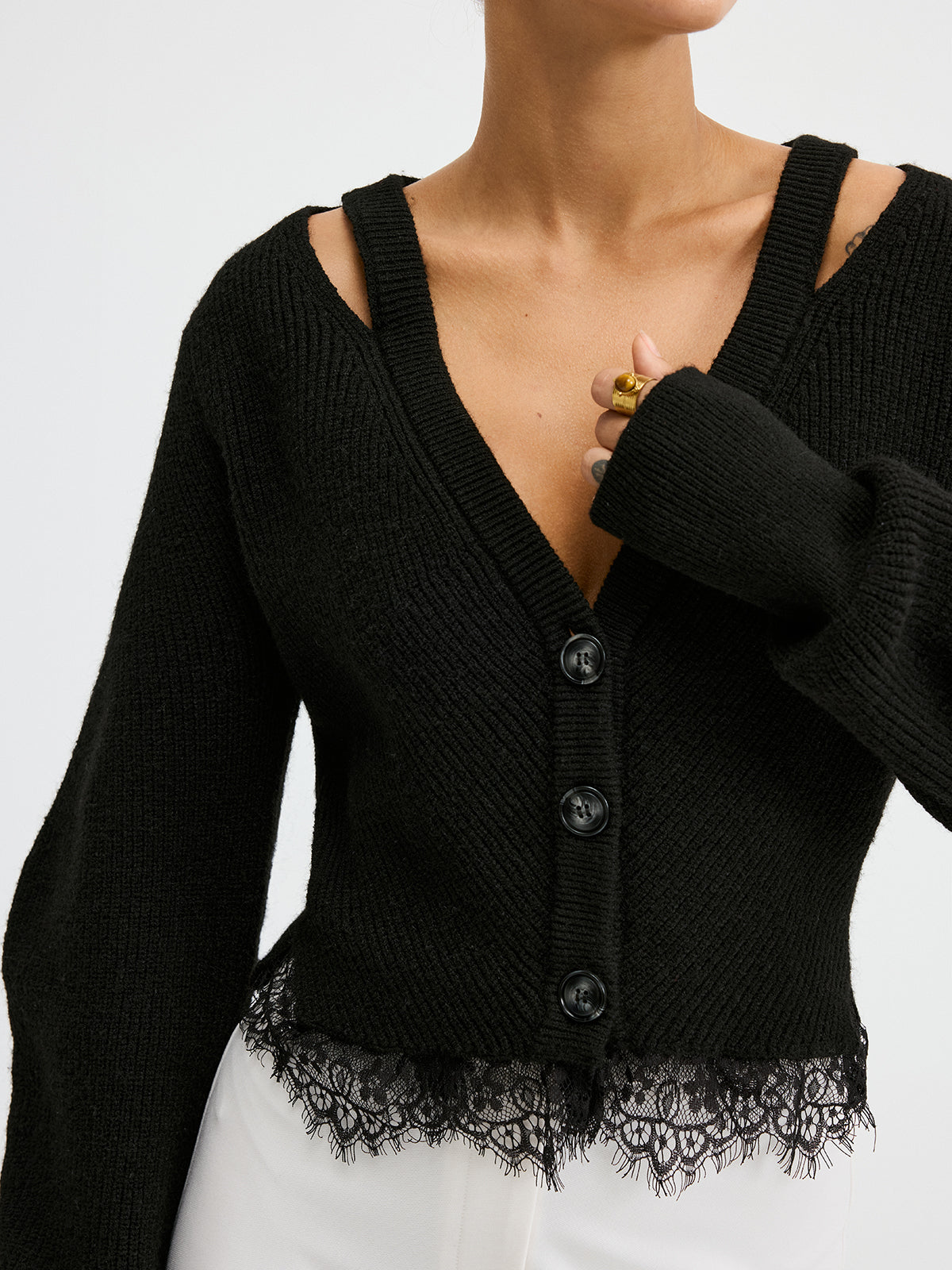 KOAD'CLO wool blend cardigan with lace hem, cut-out shoulders, white pants.