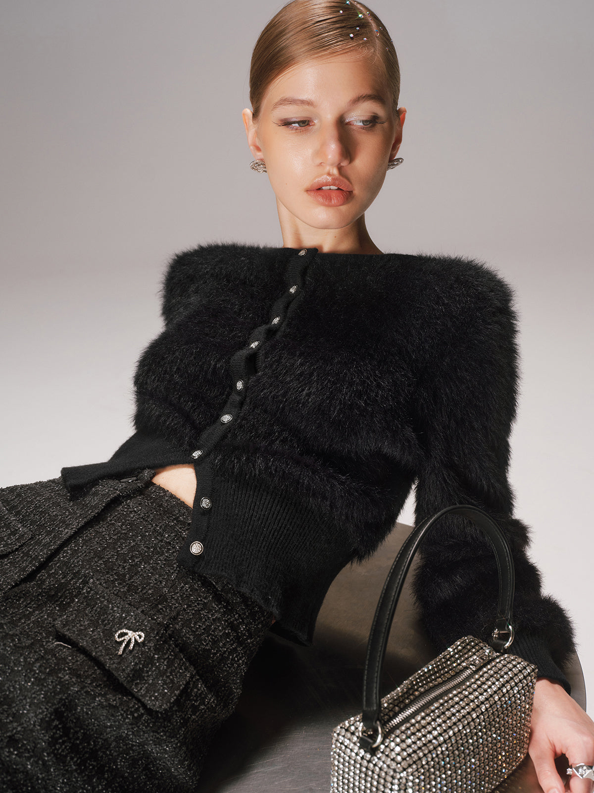 A cropped faux mink cardigan with button-front, paired with textured, dark-colored pants.