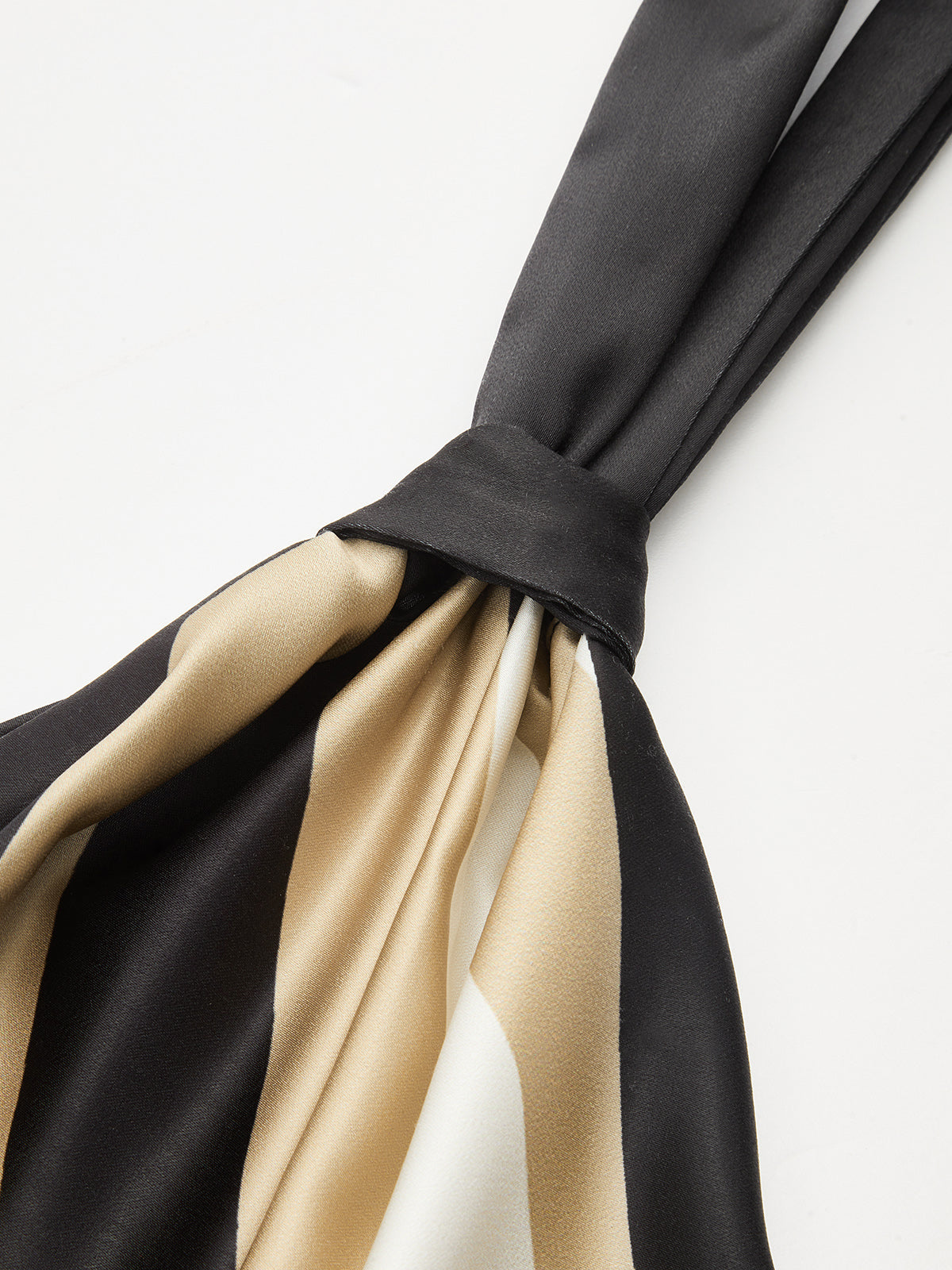 Geometric-stripe satin halter top with asymmetric hem, scarf-style cut, and adjustable neck tie.
